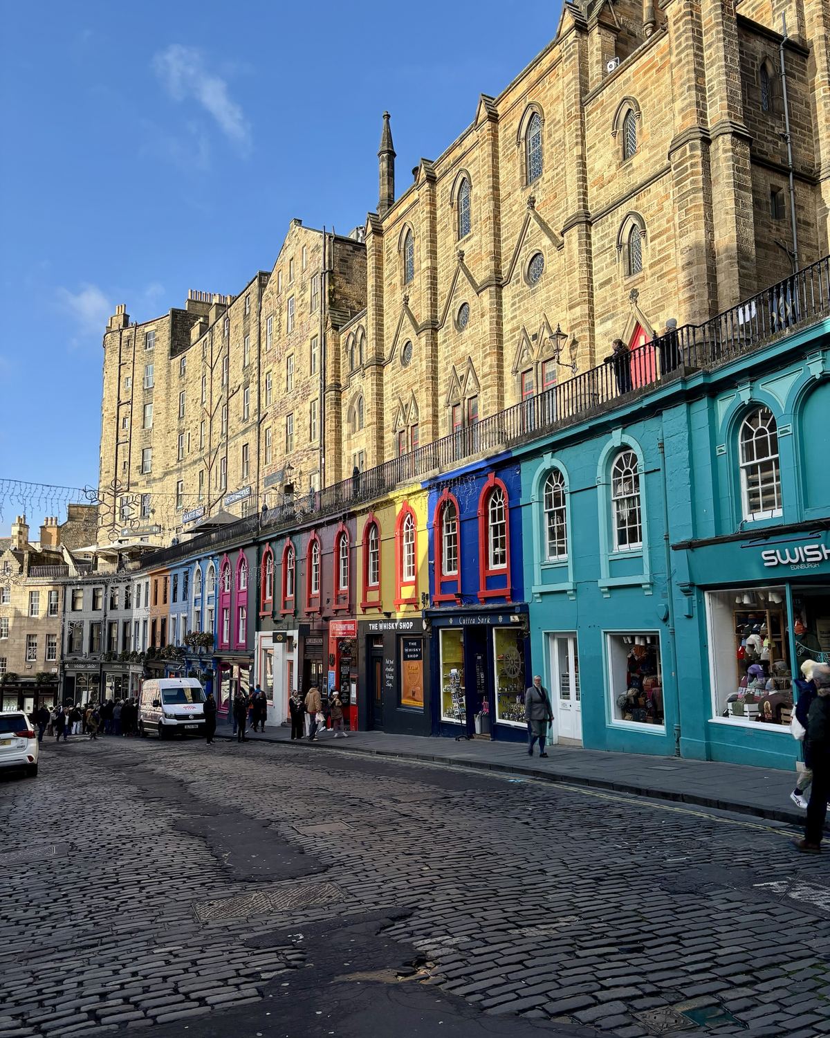 Victoria Street in Edinburgh met kleurrijke winkelpuien onder een blauwe lucht