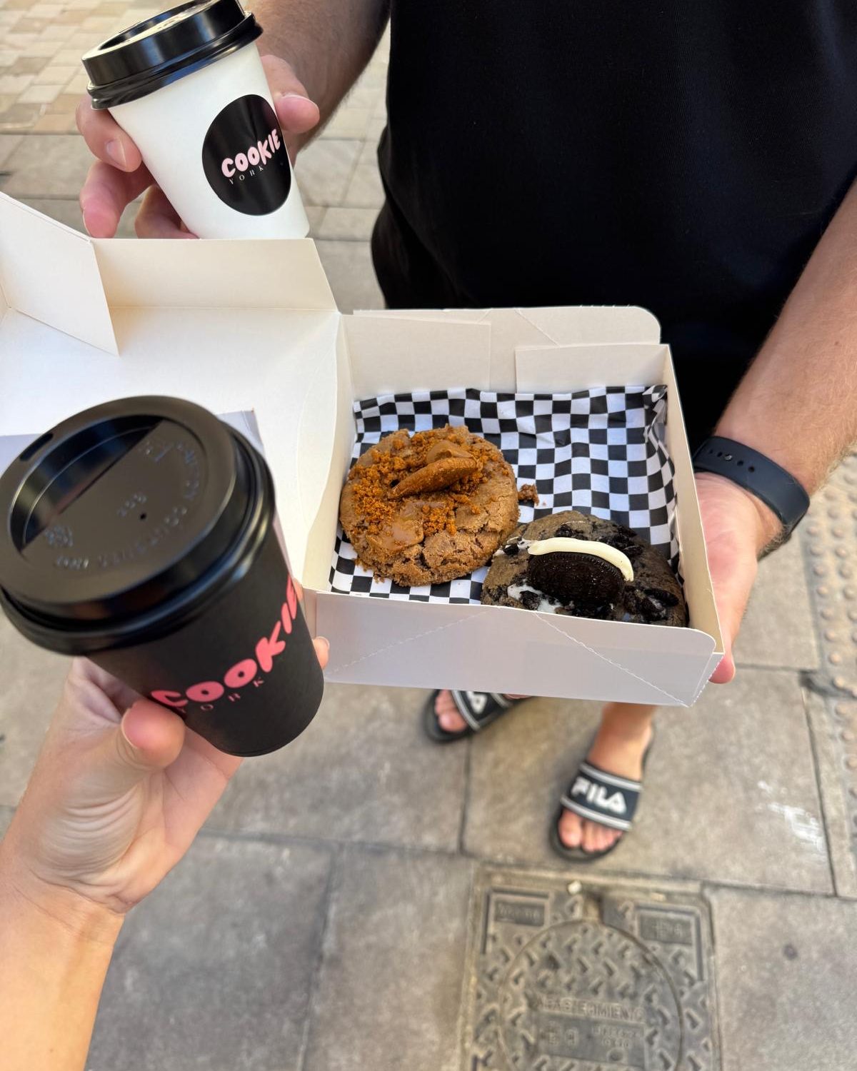 Twee bekers koffie en een doosje met koeken op straat in Málaga