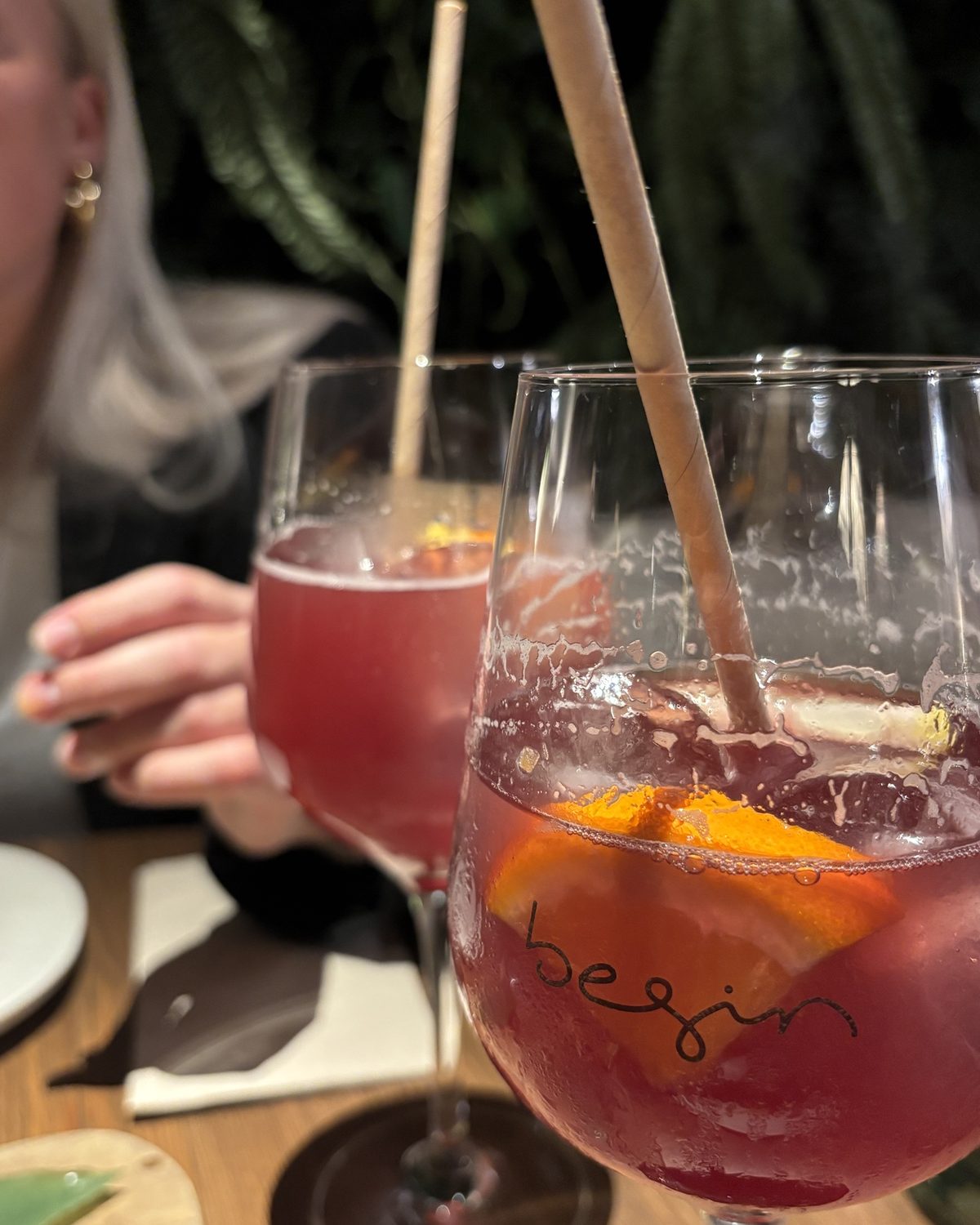 Twee glazen met een rood drankje en een schijfje sinaasappel op tafel bij restaurant Begin